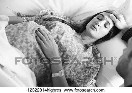 A husband stands by the bedside of his pregnant wife during labour; Oregon, United States of America View Large Photo Image Stock Photograph - A husband stands by the bedside of his pregnant wife during labour; Oregon, United States of America. Fotosearch