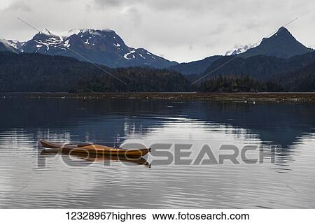 A kayak sits on the tranquil water with a view of forests and a mountain range in the background, Kachemak Bay State Park; Alaska, United States of America View Large Photo Image Stock Photograph - A kayak sits on the tranquil water with a view of forests and a mountain range in the background, Kachemak Bay State Park; Alaska, United States of America. Fotosearch