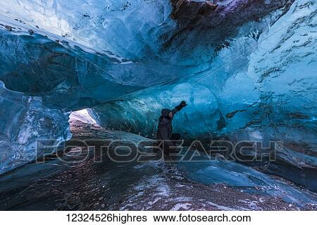 A man examines the clear blue ice inside a tunnel beneath the surface of Black Rapids Glacier in winter; Alaska, United States of America View Large Photo Image Stock Photograph - A man examines the clear blue ice inside a tunnel beneath the surface of Black Rapids Glacier in winter; Alaska, United States of America. Fotosearch