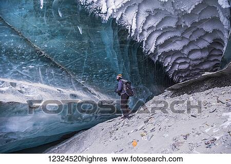 A man explores a tunnel beneath the ice of Canwell Glacier in the Alaska Range in winter; Alaska, United States of America View Large Photo Image Stock Photograph - A man explores a tunnel beneath the ice of Canwell Glacier in the Alaska Range in winter; Alaska, United States of America. Fotosearch