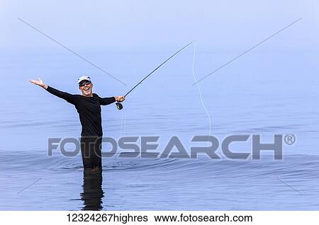Stock Photograph - A man fly fishing and posing with an excited look on his face; Port McNeill, British Columbia, Canada. Fotosearch