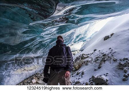 A man looks up at the ice of Canwell Glacier while standing in the entrance to an ice cave; Alaska, United States of America View Large Photo Image Stock Photograph - A man looks up at the ice of Canwell Glacier while standing in the entrance to an ice cave; Alaska, United States of America. Fotosearch