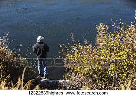 A man stands fishing on the shore of a lake; Oregon, United States of America View Large Photo Image Stock Photograph - A man stands fishing on the shore of a lake; Oregon, United States of America. Fotosearch