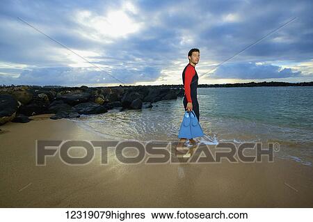 A man walks into the water from Lydgate Beach holding flippers; Kauai, Hawaii, United States of America View Large Photo Image Stock Photograph - A man walks into the water from Lydgate Beach holding flippers; Kauai, Hawaii, United States of America. Fotosearch