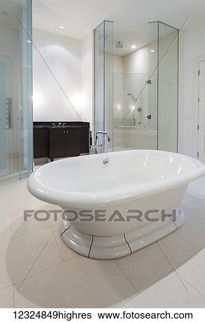 A modern bathroom with a tub floating in the middle of the room and glass shower doors; Ontario, Canada View Large Photo Image Stock Photograph - A modern bathroom with a tub floating in the middle of the room and glass shower doors; Ontario, Canada. Fotosearch