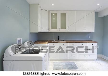 Stock Photograph - A new residential laundry room with white cabinets and blue walls; Grimsby, Ontario, Canada. Fotosearch