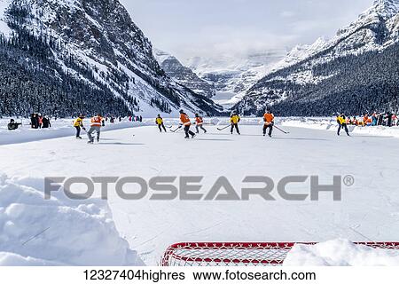 Stock Photograph - A pair of hockey teams compete in pond hockey on Lake Louise at the Fairmont Chateau Lake Louise pond hockey tournament in the winter; Lake Louise, Alberta, Canada. Fotosearch