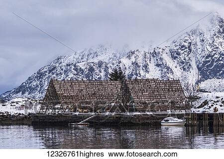 A peaked structure on the water's edge providing shelter for equipment with a boat moored in the water; Svolvar, Lofoten Islands, Nordland, Norway View Large Photo Image Stock Photograph - A peaked structure on the water's edge providing shelter for equipment with a boat moored in the water; Svolvar, Lofoten Islands, Nordland, Norway. Fotosearch