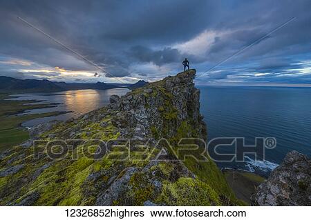 A person stands and looks at the view from the top of a sea cliff along the Strandir Coast; West Fjords, Iceland View Large Photo Image Stock Photograph - A person stands and looks at the view from the top of a sea cliff along the Strandir Coast; West Fjords, Iceland. Fotosearch