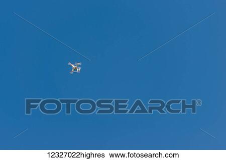 Stock Photograph - A quadcopter in flight in a blue sky; Georgia. Fotosearch