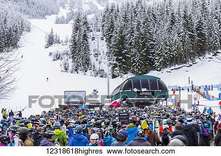 Stock Photograph - A record crowd of waiting ski and s0wboard visitors at the Creekside Gondola chair lift in Whistler Mountain on a winter long weekend with fresh s0wfall; Whistler, British Columbia, Canada. Fotosearch