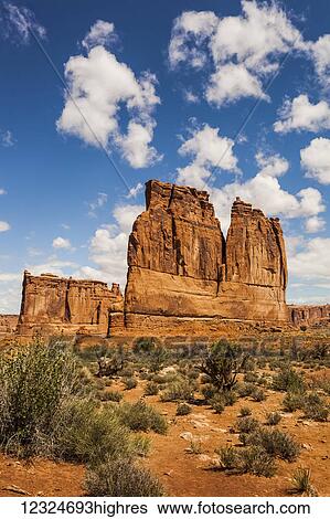 Stock Photograph - A rugged rock formation in the desert under blue sky with cloud; Arizona, United States of America. Fotosearch