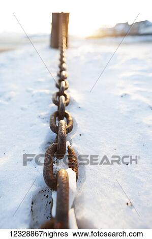 Stock Photograph - A rusty metal chain laying in the snow; Alaska, United States of America. Fotosearch