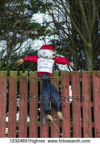 Stock Photograph - A scarecrow sits on a fence with a sign reading 'scare away the developers'; South Shields, Tyne and Wear, England. Fotosearch