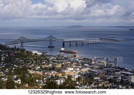 Stock Photograph - A ship passes the Astoria waterfront; Astoria, Oregon, United States of America. Fotosearch