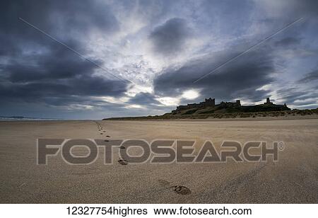 Stock Photograph - A single set of footprints on the beach with Bamburgh Castle in the background; Bamburgh, Northumberland, England. Fotosearch