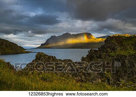 Stock Photograph - A small rainbow is seen along the Strandir Coast; West Fjords, Iceland. Fotosearch
