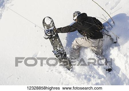 A snowboarder climbs steep terrain in deep snow with his snowboard; Alaska, United States of America View Large Photo Image Stock Photograph - A snowboarder climbs steep terrain in deep snow with his snowboard; Alaska, United States of America. Fotosearch