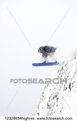 A snowboarder jumps off a mountain cliff; Alaska, United States of America View Large Photo Image Stock Photograph - A snowboarder jumps off a mountain cliff; Alaska, United States of America. Fotosearch