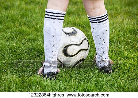 A soccer player standing on a grass field with a soccer ball and mud splashed socks; Oregon, United States of America View Large Photo Image Stock Photograph - A soccer player standing on a grass field with a soccer ball and mud splashed socks; Oregon, United States of America. Fotosearch