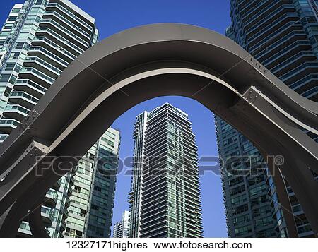 A steel arch in the foreground with residential skyscrapers against a blue sky in the background; Toronto, Ontario, Canada View Large Photo Image Stock Photograph - A steel arch in the foreground with residential skyscrapers against a blue sky in the background; Toronto, Ontario, Canada. Fotosearch