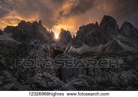 A sunstar shines through the Dolomite Mountains at sunset near Cortina; Italy View Large Photo Image Stock Photograph - A sunstar shines through the Dolomite Mountains at sunset near Cortina; Italy. Fotosearch