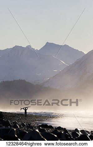 A surfer carries her surfboard across the beach in the mist along the coast; Homer, Alaska, United States of America View Large Photo Image Stock Photograph - A surfer carries her surfboard across the beach in the mist along the coast; Homer, Alaska, United States of America. Fotosearch