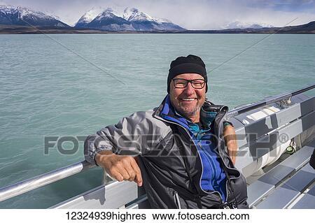 A tourist sits on a boat and poses for a picture on a cruise of Lake Argentino near El Calafate, Argentinian Patagonia; El Calafate, Santa Cruz Province, Argentina View Large Photo Image Stock Photograph - A tourist sits on a boat and poses for a picture on a cruise of Lake Argentino near El Calafate, Argentinian Patagonia; El Calafate, Santa Cruz Province, Argentina. Fotosearch