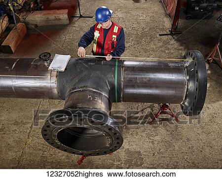 Stock Photograph - A tradesman measures a pipe for documentation; Edmonton, Alberta, Canada. Fotosearch