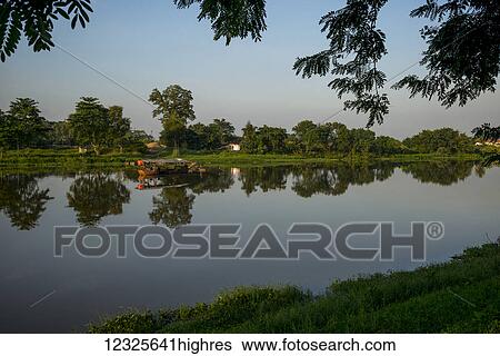A tranquil scene with trees reflected in the river water and a blue sky; Chiang Rai, Thailand View Large Photo Image Stock Photograph - A tranquil scene with trees reflected in the river water and a blue sky; Chiang Rai, Thailand. Fotosearch