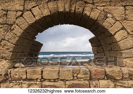 A wall of stone blocks with arch framing a view of the Mediterranean sea along the coast; Jisr az-Zarqa, Haifa District, Israel View Large Photo Image Stock Photograph - A wall of stone blocks with arch framing a view of the Mediterranean sea along the coast; Jisr az-Zarqa, Haifa District, Israel. Fotosearch