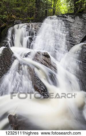 Stock Photograph - A waterfall splashing down a rocky embankment in a forest; Middle Sackville, Nova Scotia, Canada. Fotosearch
