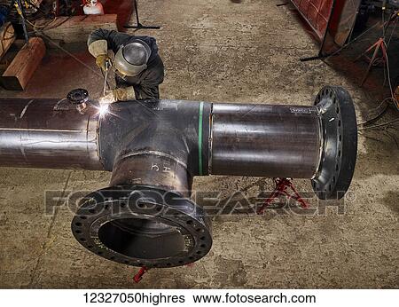 Stock Photograph - A welder works on welding the joints of pipes; Edmonton, Alberta, Canada. Fotosearch