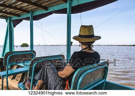Stock Photograph - A woman sits on a boat looking out at the water as it tours down a river; Siem Reap Province, Cambodia. Fotosearch