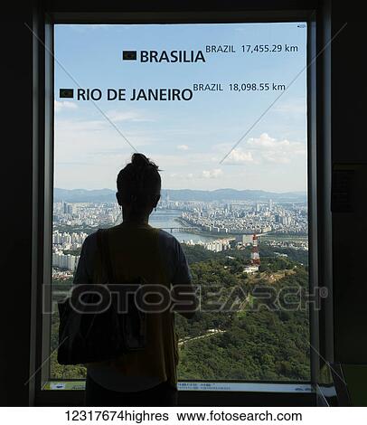A woman stands at the window of Seoul Tower with a view of the city of Seoul; Seoul, South Korea View Large Photo Image Stock Photograph - A woman stands at the window of Seoul Tower with a view of the city of Seoul; Seoul, South Korea. Fotosearch