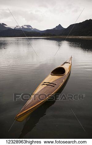 A wooden kayak sits on tranquil water with a view of the mountains in the background, Kachemak Bay State Park; Alaska, United States of America View Large Photo Image Stock Photograph - A wooden kayak sits on tranquil water with a view of the mountains in the background, Kachemak Bay State Park; Alaska, United States of America. Fotosearch