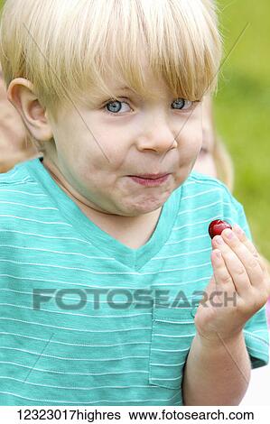 Stock Photograph - A young boy with a funny facial expression after tasting a sour berry; Oregon, United States of America. Fotosearch