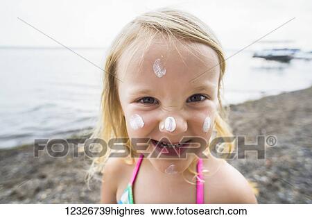 Stock Photograph - A young Caucasian girl with sunscreen on her face poses for a picture at Seneca Lake; Dresden, New York, United States of America. Fotosearch