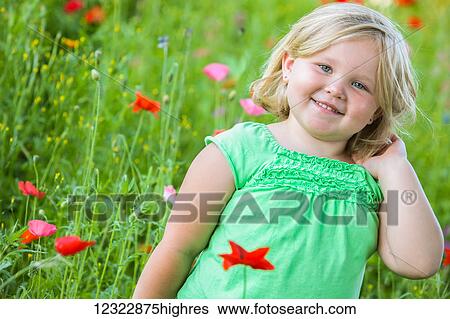 Stock Photograph - A young girl with blond hair stands in a field of colourful poppies; Oregon, United States of America. Fotosearch