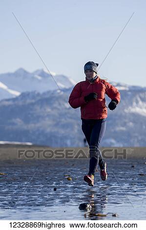 A young woman jogs along the wet beach in winter; Homer, Alaska, United States of America View Large Photo Image Stock Photograph - A young woman jogs along the wet beach in winter; Homer, Alaska, United States of America. Fotosearch