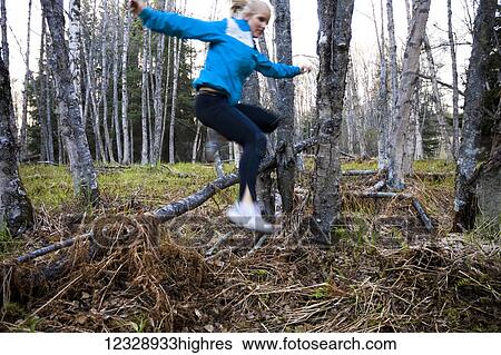 A young woman leaps across a fallen tree on a forest floor while running in a forest; Homer, Alaska, United States of America View Large Photo Image Stock Photograph - A young woman leaps across a fallen tree on a forest floor while running in a forest; Homer, Alaska, United States of America. Fotosearch