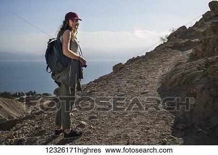 A young woman poses while hiking in Ein Gedi, with the Dead Sea in the background, Dead Sea District; South District, Israel View Large Photo Image Stock Photograph - A young woman poses while hiking in Ein Gedi, with the Dead Sea in the background, Dead Sea District; South District, Israel. Fotosearch