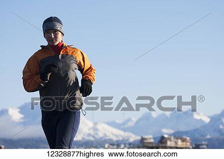A young woman running with a snow covered mountain range in the background; Homer, Alaska, United States of America View Large Photo Image Stock Photograph - A young woman running with a snow covered mountain range in the background; Homer, Alaska, United States of America. Fotosearch