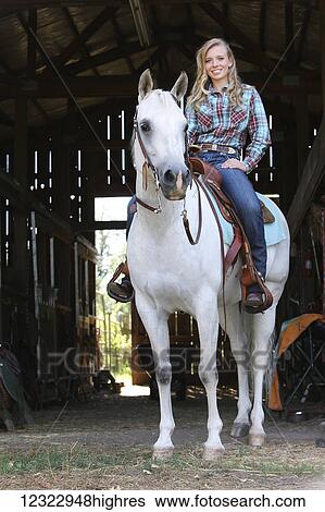 Stock Photograph - A young woman sitting on a white horse; Oregon, United States of America. Fotosearch