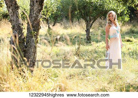 A young woman with blond hair and a flowing dress stands in a field with tall grass; Oregon, United States of America View Large Photo Image Stock Photograph - A young woman with blond hair and a flowing dress stands in a field with tall grass; Oregon, United States of America. Fotosearch