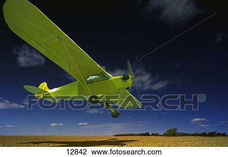 Stock Image - airplane flying low over farmland. Fotosearch