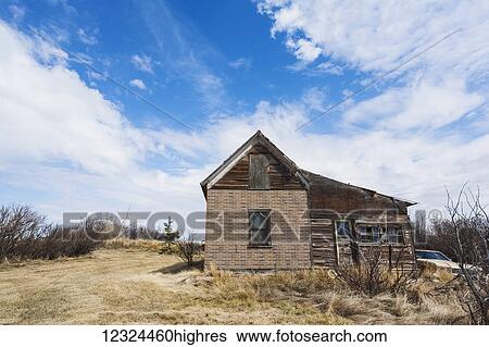 Stock Photograph - An old, abandoned wooden house and vintage car on the prairies; Alberta, Canada. Fotosearch