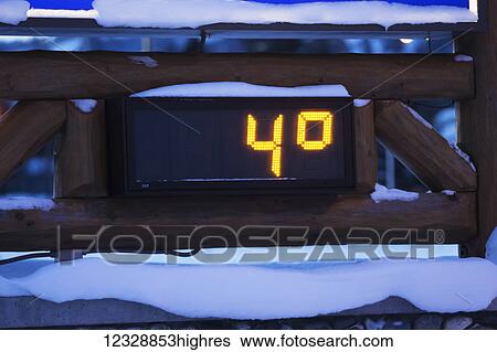 Stock Photograph - An outdoor digital thermometer in the snow in winter measuring four degrees fahrenheit; Alaska, United States of America. Fotosearch