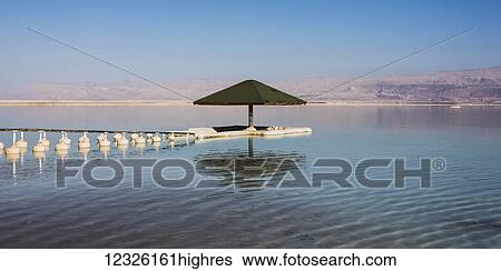 Stock Photograph - An umbrella, buoys and a dock in the Dead Sea; South District, Israel. Fotosearch