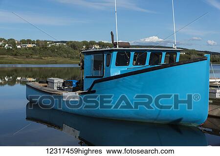 Stock Photograph - Blue boat moored against a dock in Inverness Harbour; Mabou, 0va Scotia, Canada. Fotosearch
